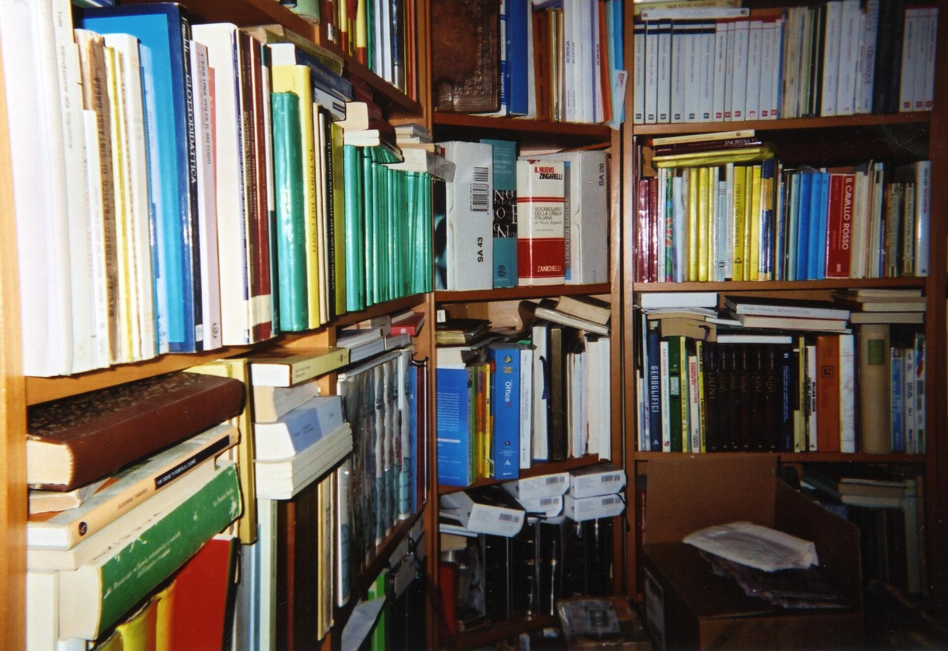 Kolorowe grzbiety książek na półkach bibliotecznych.